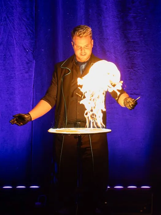 A fire bubble in his hands against a purple curtain